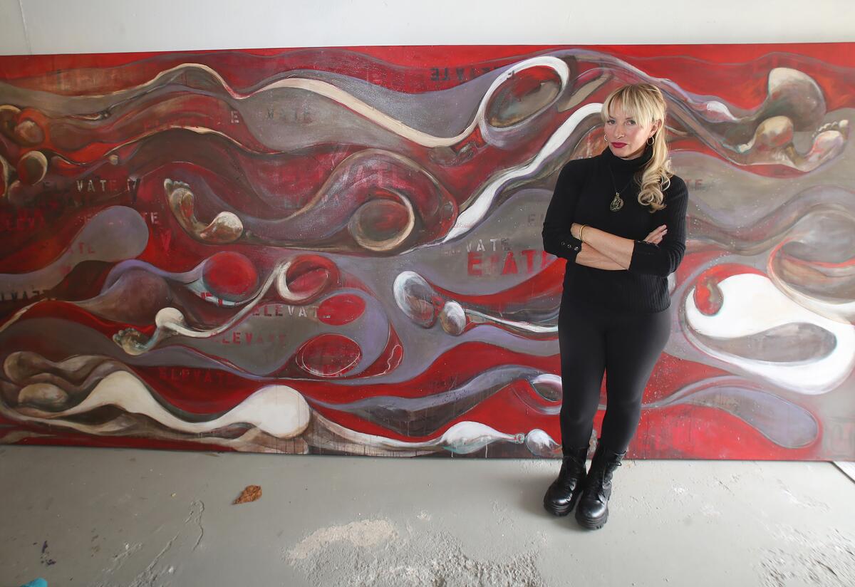 Local artist Christiana Lewis Ulwelling stands next to her painting, "Elevate."