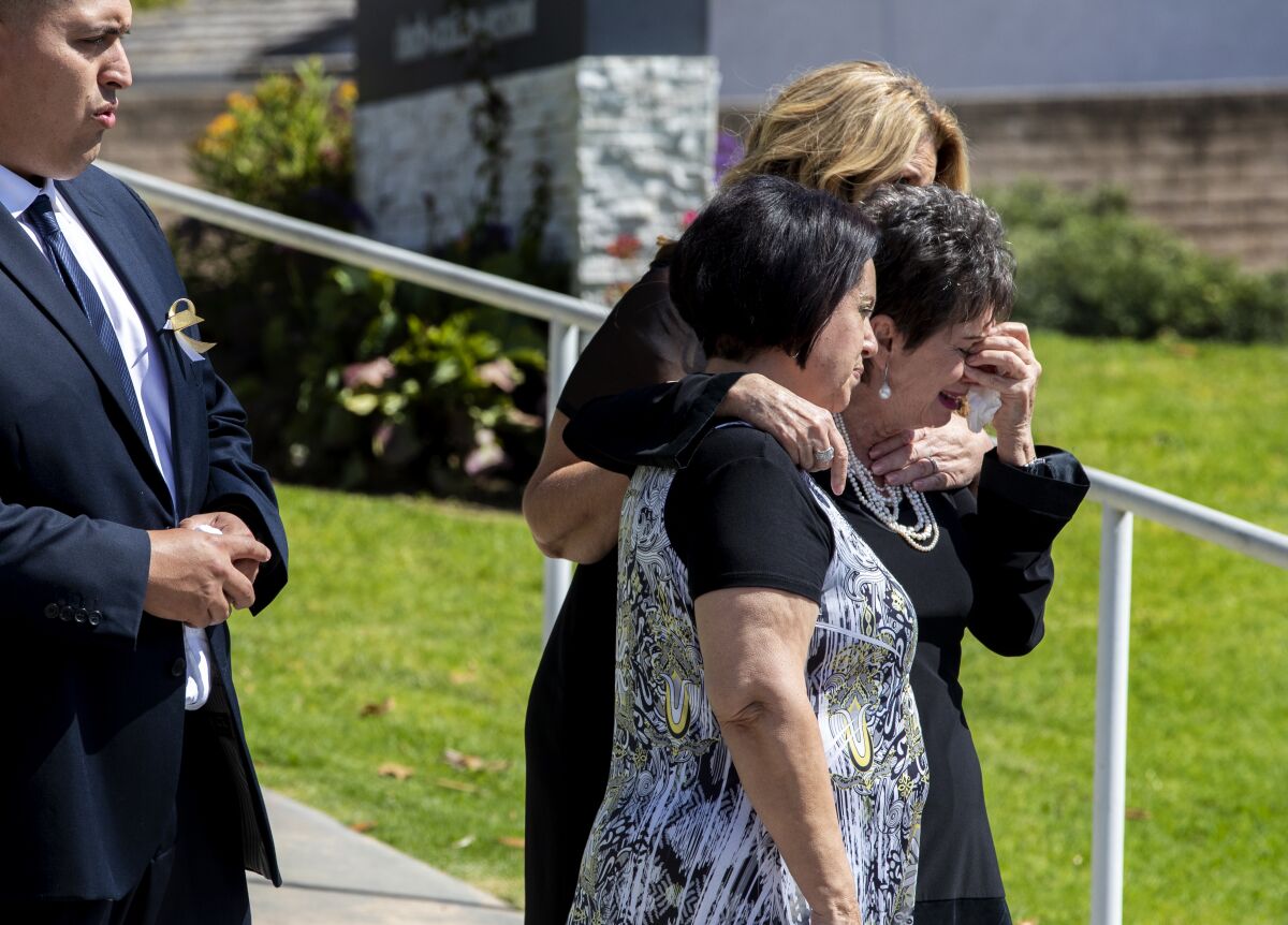 Family members grieve as the casket of 6-year-old Aiden Leos is put into a hearse.