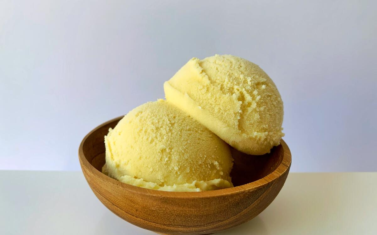 Two scoops of custard ice cream in a wooden bowl.