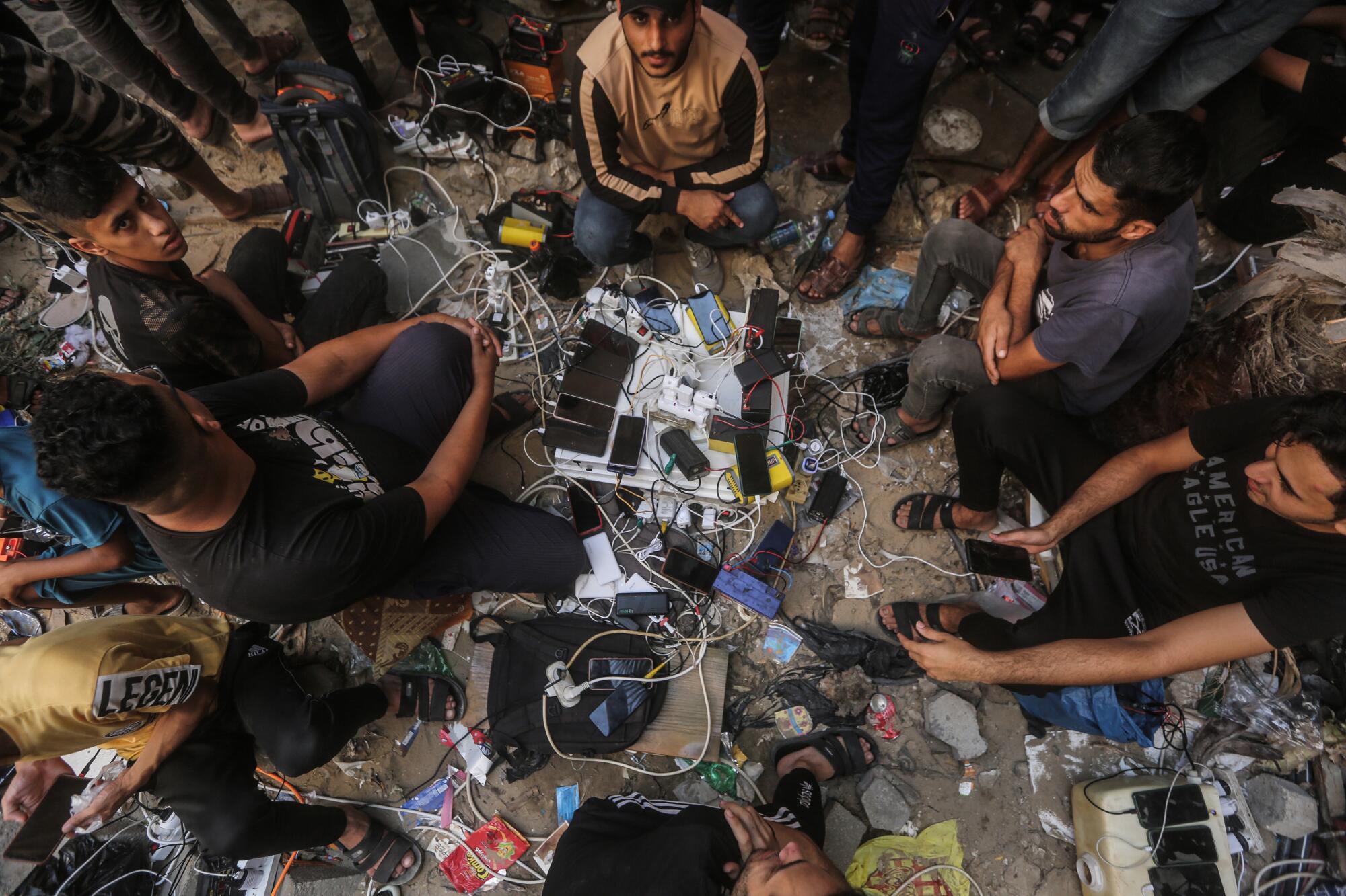 Palestinians who fled to southern Gaza to escape Israeli airstrikes charge their phones