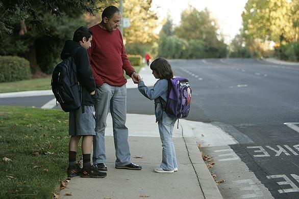 Anwer Shalchi waits with his daughter Mouna and a neighbor's son for the school bus in Folsom, Calif., the Salchis' adopted home.