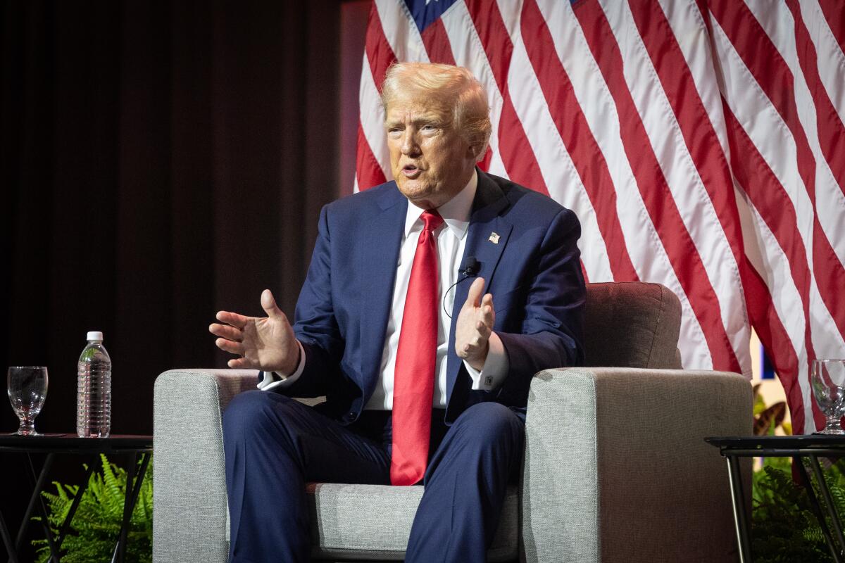 Trump holds his hands out as he speaks from an armchair.