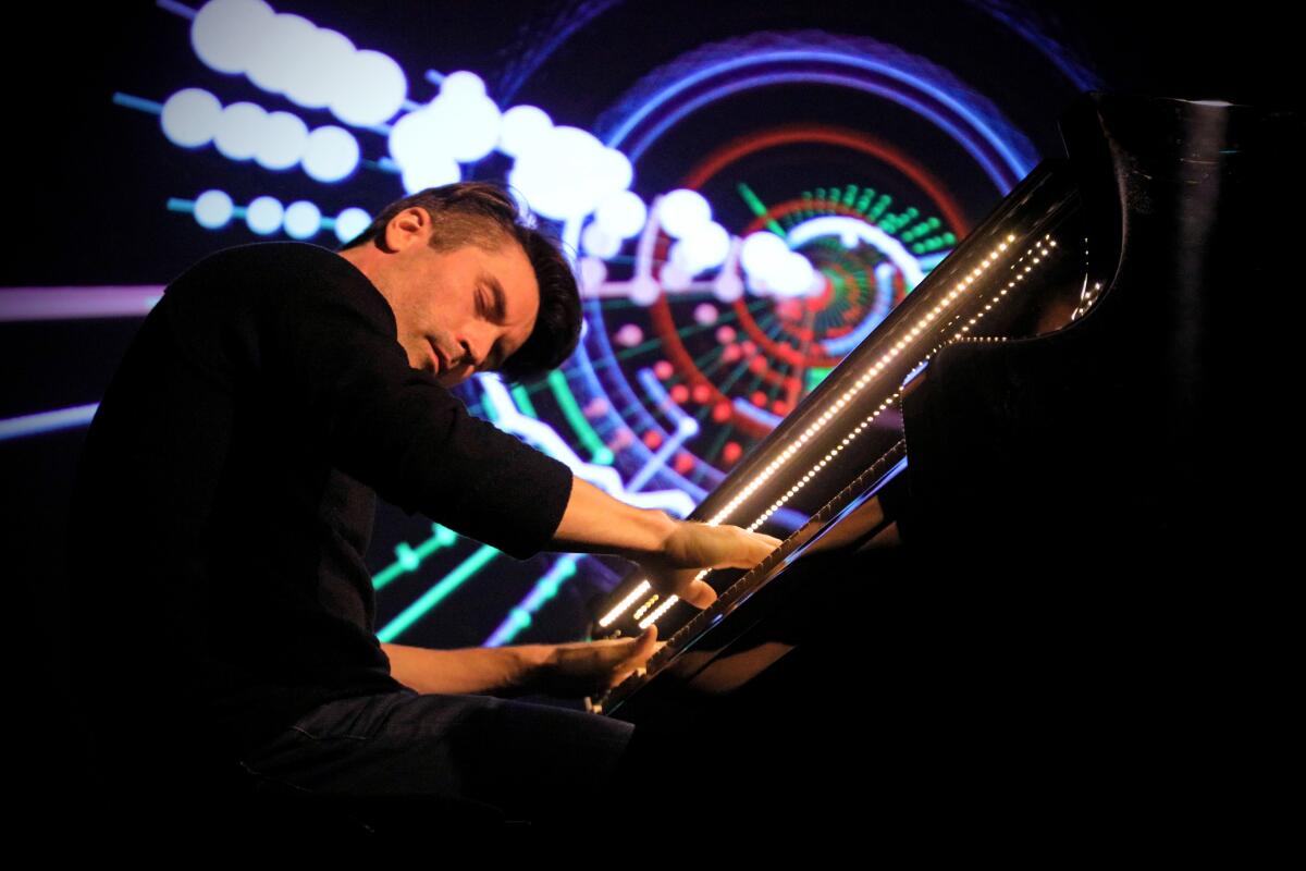 A man playing on the piano with colorful lights behind him. 
