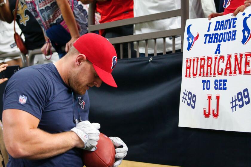 Houston Texans defensive end J.J. Watt signs autographs for fans holding sings referencing Hurricane Harvey before an NFL football game against the New Orleans Saints in New Orleans, Saturday, Aug. 26, 2017. (AP Photo/Butch Dill)