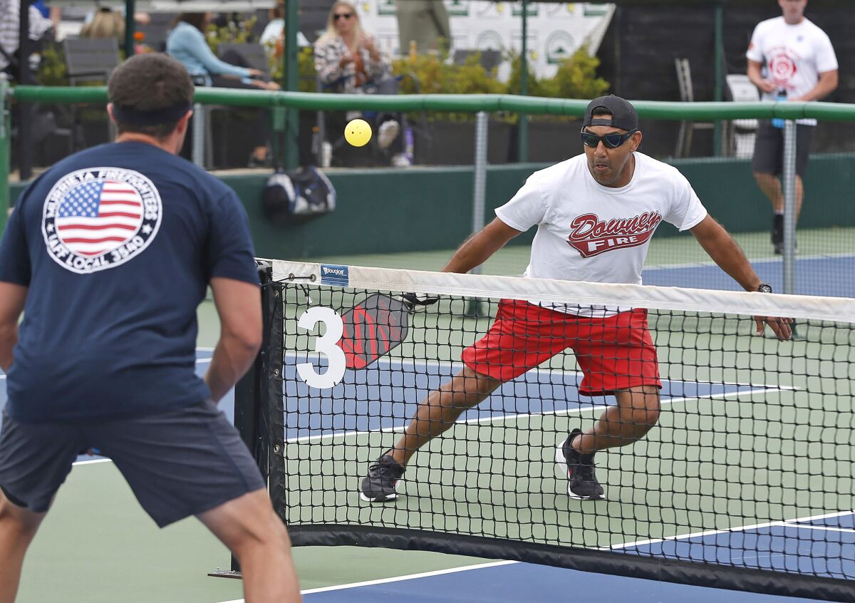 Downey firefighter Tacho Rios, right, runs down a ball during the inaugural First Responders Pickleball Tournament.