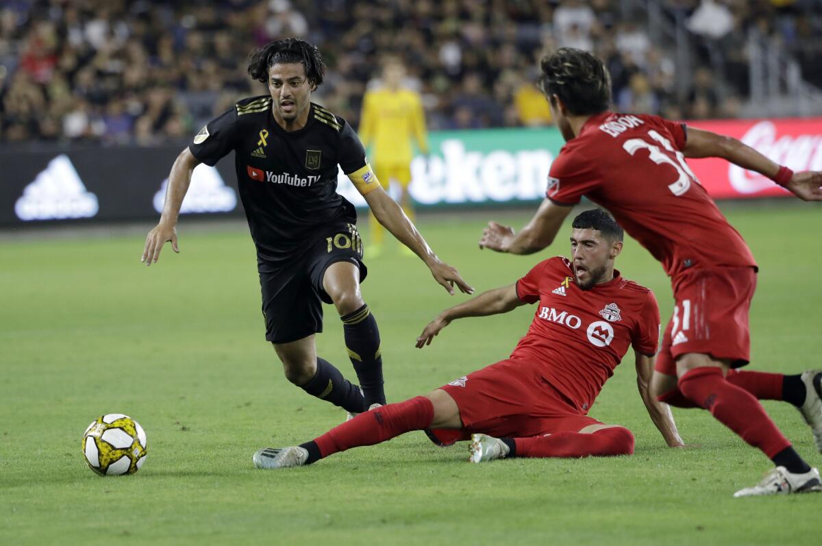 Los Angeles FC's Carlos Vela, left, is defended by Toronto FC's Jonathan Osorio, bottom center, during the second half of an MLS soccer match Saturday, Sept. 21, 2019, in Los Angeles. (AP Photo/Marcio Jose Sanchez)
