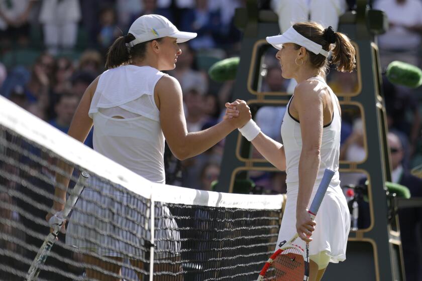 Alize Cornet, right, shakes hands with Iga Swiatek after defeating her in a third-round Wimbledon match July 2, 2022.
