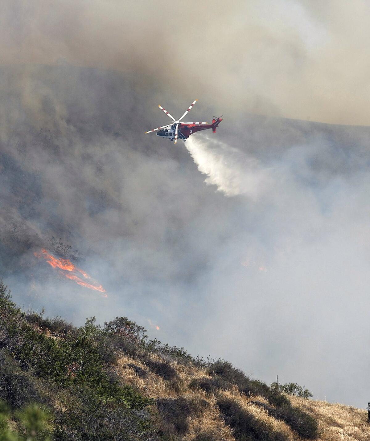 A helicopter makes a water drop on a brush fire in the Chevy Chase Canyon area of Glendale on Friday, May 3, 2013.