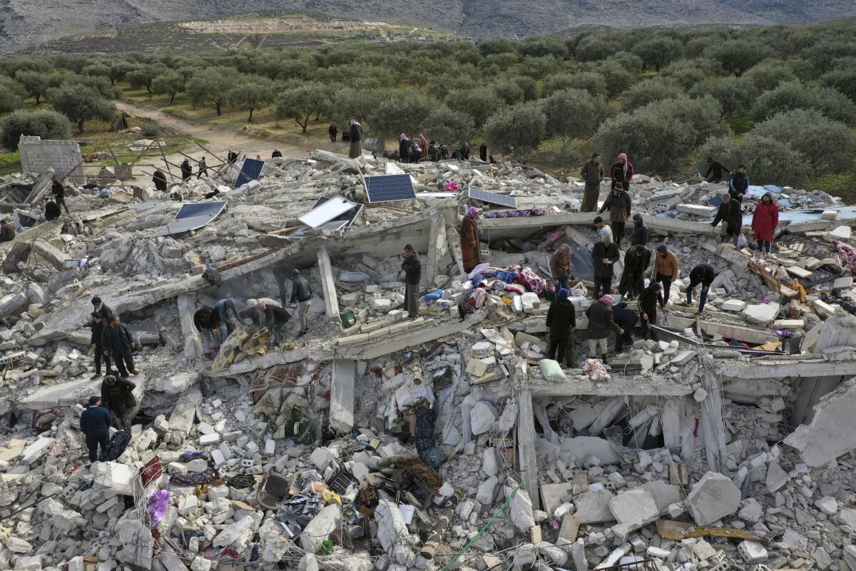 People stand on top of a huge pile of rubble.
