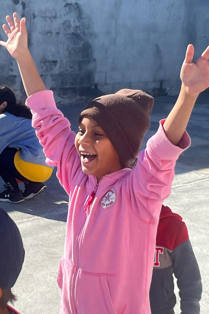 来自危地马拉的 9 岁移民瓦莱里·加西亚 (Valeri Garcia) 在墨西哥雷诺萨的避难所踢足球时微笑。