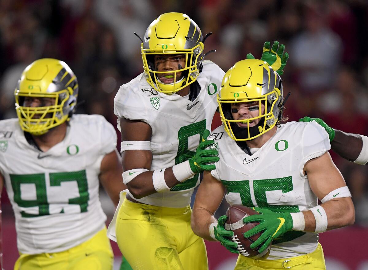 Oregon's Brady Breeze (25) celebrates with teammates Jevon Holland (8) and Sione Kava (93) after returning an interception for a touchdown.