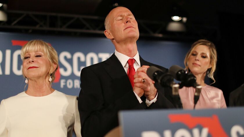 Florida Gov. Rick Scott, flanked by wife Ann and daughter Alison Guimard, becomes emotional while speaking at his election night party in Naples, Fla.