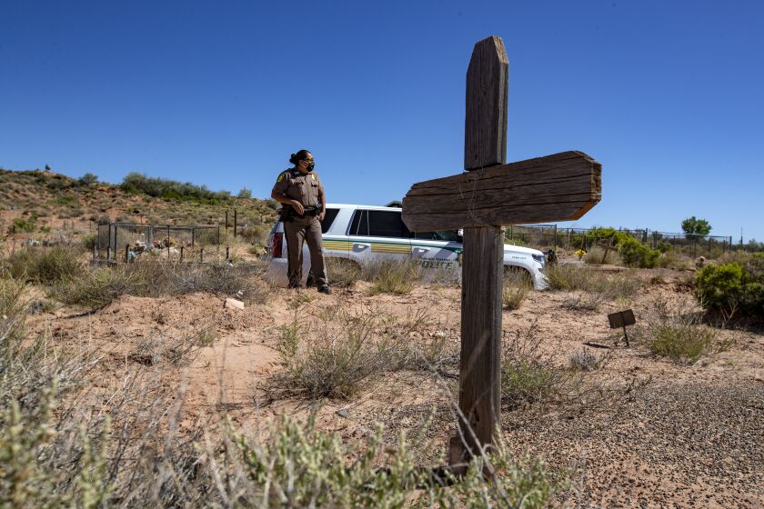TUBA CITY, AZ - MAY 22: Navajo Nation police officer Carolyn Tallsalt looks out at dried sagebrush where her uncle George Billy was buried in April at the Tuba City Community Cemetery on Friday, May 22, 2020 in Tuba City, AZ. Lockdown curfews are being enforced over the weekends in an effort to slow the coronavirus' spread. (Brian van der Brug / Los Angeles Times)