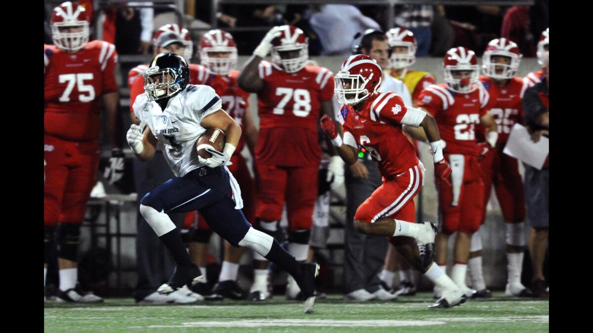 St. John Bosco running back Sean McGrew breaks free from Mater Dei's Jalen Cole to score on a long run during a Trinity League game on Oct. 16.