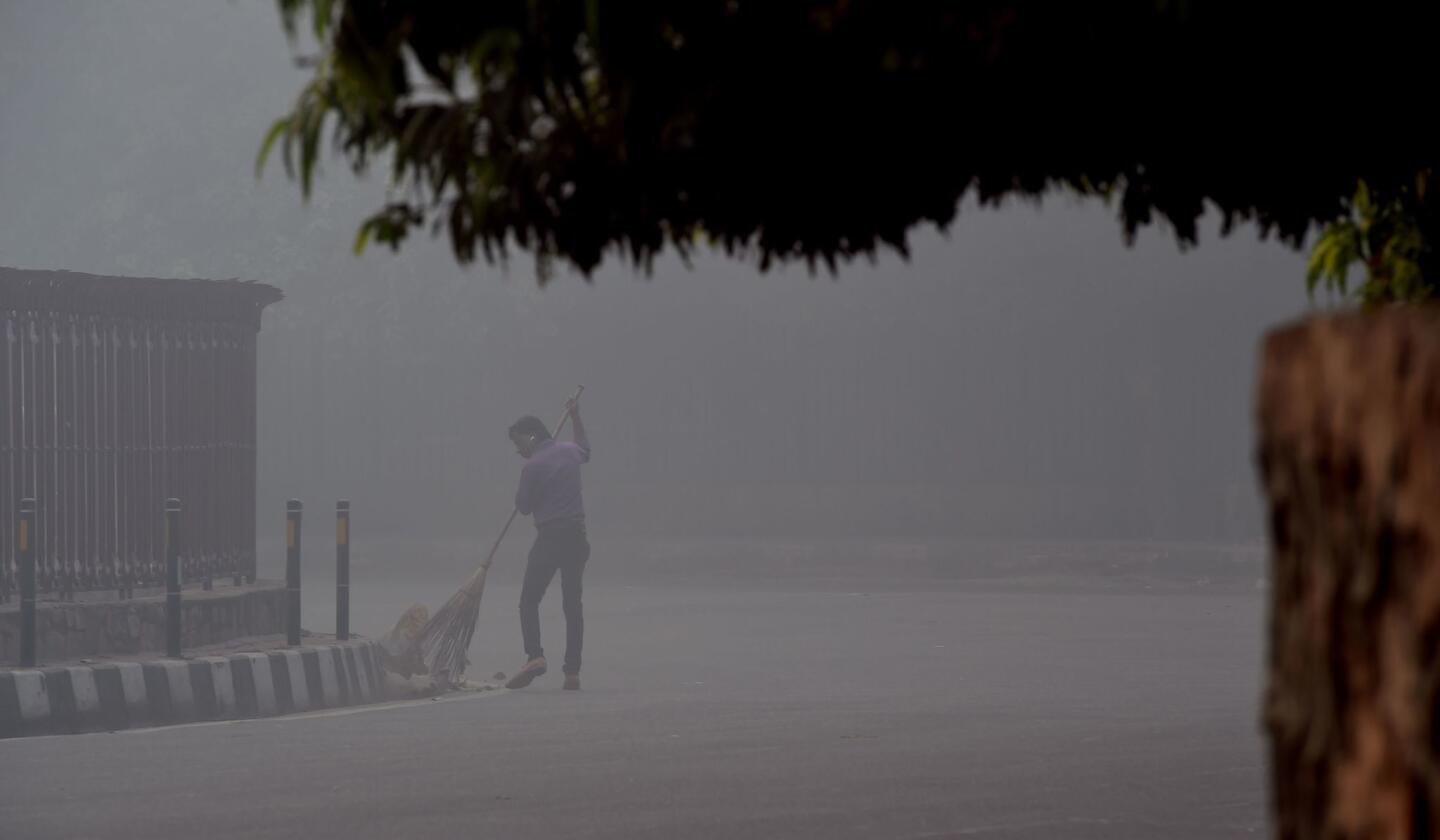 An Indian worker sweeps a street as smog envelops a street in New Delhi, the day after the Diwali festival. New Delhi was shrouded in a thick blanket of toxic smog a day after millions of Indians lighted firecrackers to mark the Diwali festival.