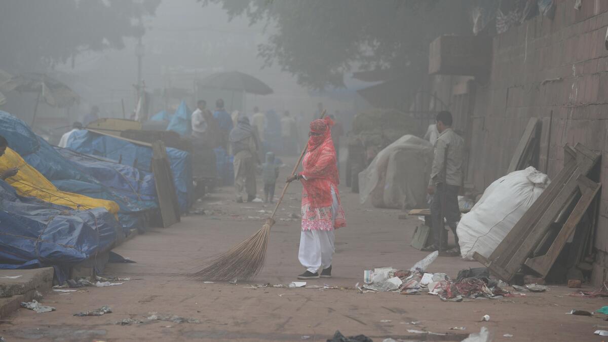 An Indian sweeper cleans a road amid heavy smog in New Delhi.
