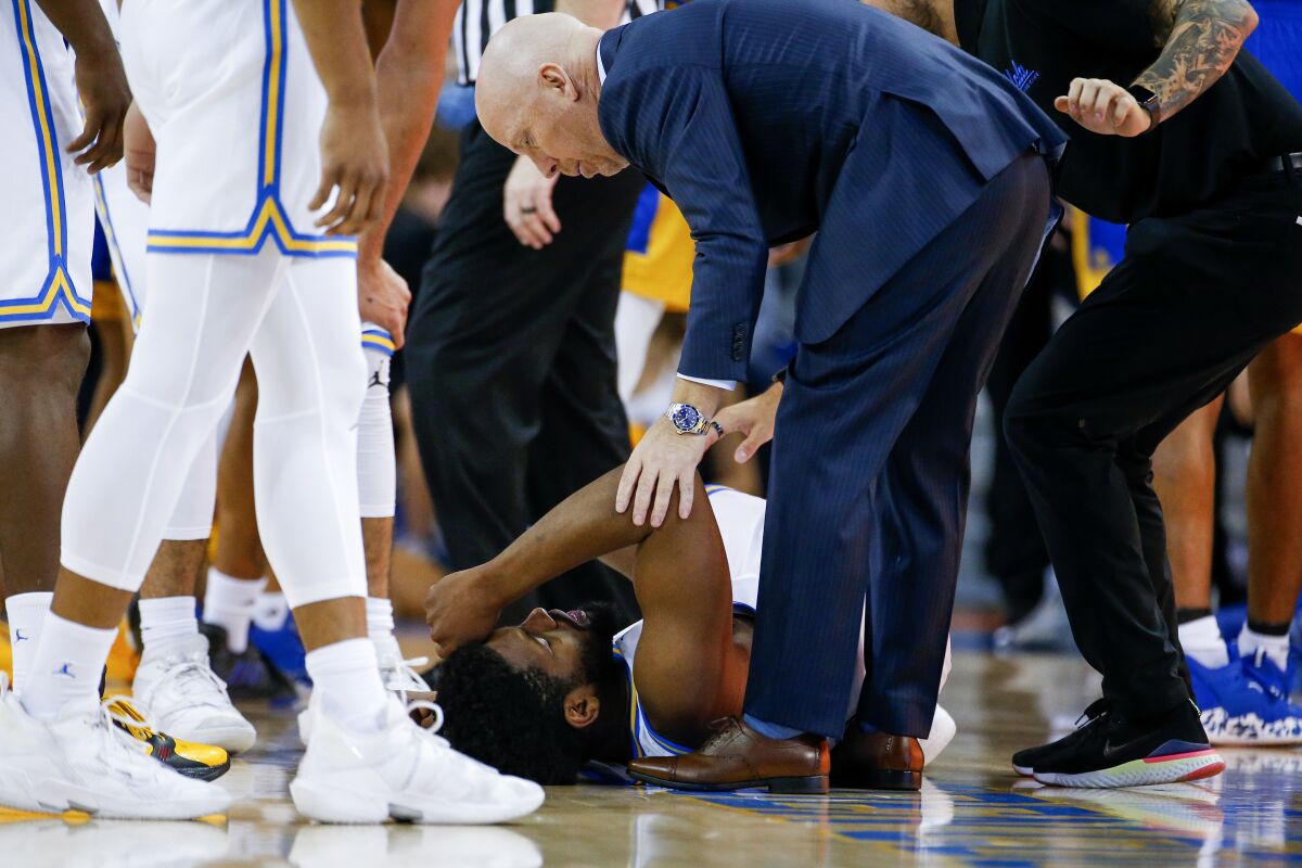 UCLA coach Mick Cronin checks with forward Cody Riley after being injured.