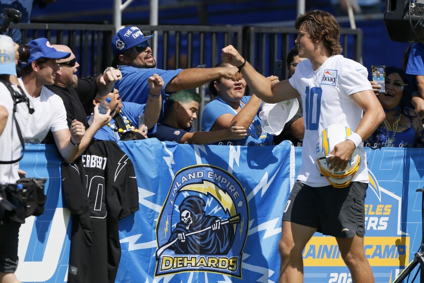 Chargers quarterback Justin Herbert high-fives fans after the first day of training camp.