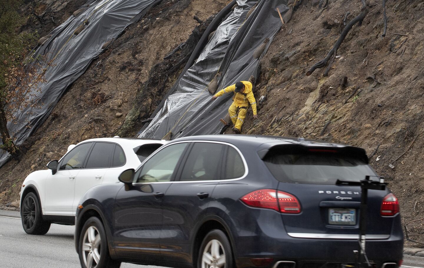 Rolly Chinan makes his way down a hillside after securing a tarp on Pacific Coast Highway in Malibu.