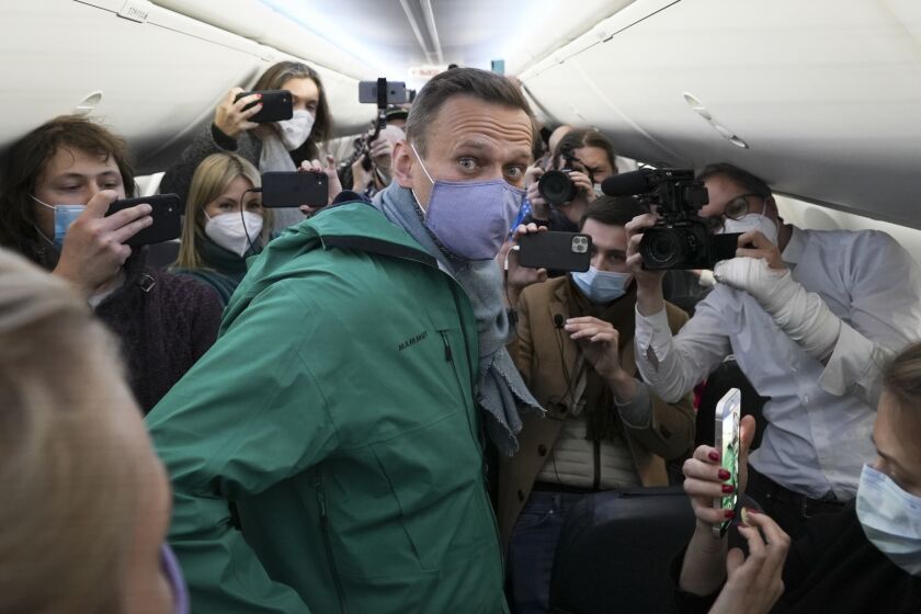 Alexei Navalny is surrounded by journalists inside the plane prior to his flight to Moscow in the Airport Berlin Brandenburg (BER) in Schoenefeld, near Berlin, Germany, Sunday, Jan. 17, 2021. Leading Kremlin critic Alexei Navalny plans to fly home to Russia on Sunday after recovering in Germany from his poisoning in August with a nerve agent. (AP Photo/Mstyslav Chernov)