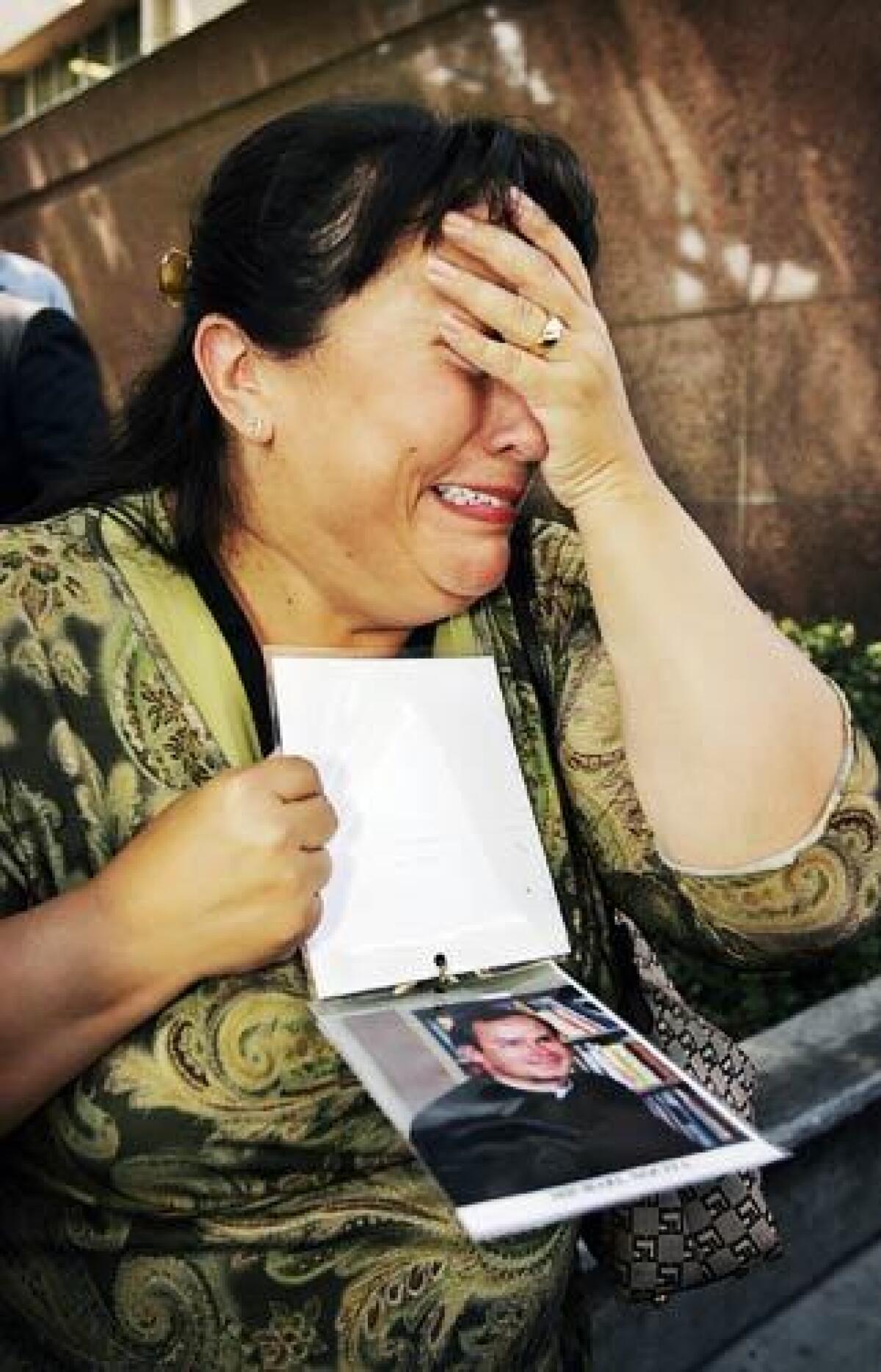 Plaintiff Esther Miller weeps while talking to the media outside Los Angeles County Superior Court. She holds a photo of Michael Nocita, the former priest she says abused her when she was a teenager in Van Nuys.