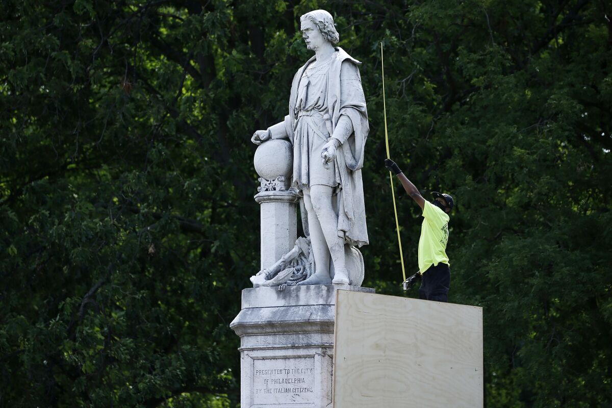 FILE - A city worker measures the statue of Christopher Columbus at Marconi Plaza in Philadelphia, June 16, 2020. A judge ruled Friday, Dec. 9, 2022, that Philadelphia must remove the plywood box it placed over the statue after 2020 protests over racial injustice. (AP Photo/Matt Slocum, File)
