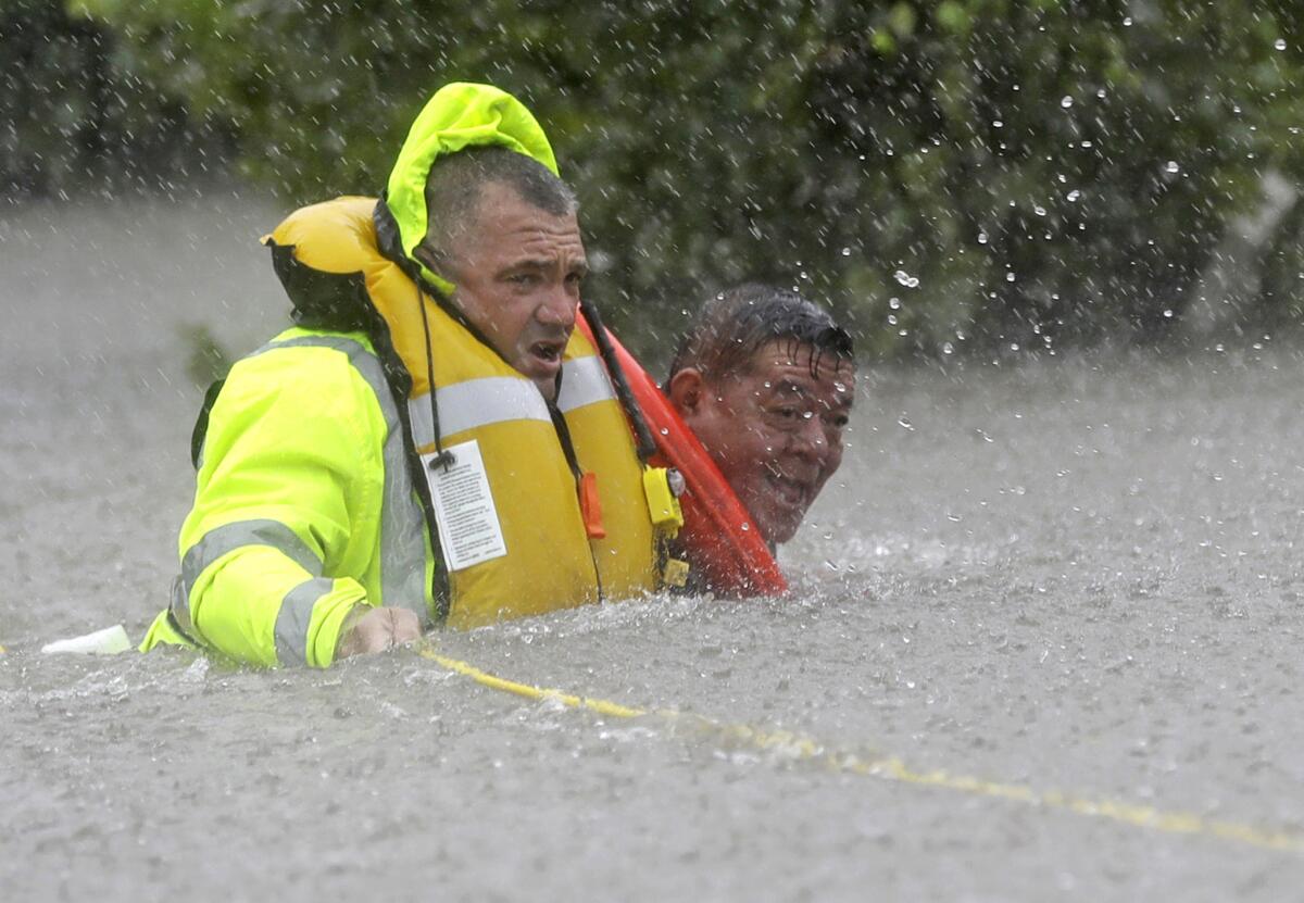 Wilford Martinez, right, is rescued from his flooded car by Richard Wagner of the Harris County Sheriff's Department along Interstate 610 in floodwaters from Tropical Storm Harvey on Sunday.