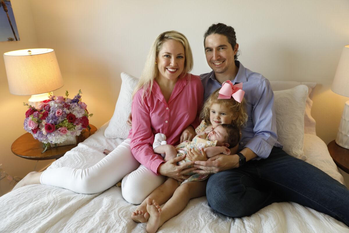 A family poses for a photo atop a bed.