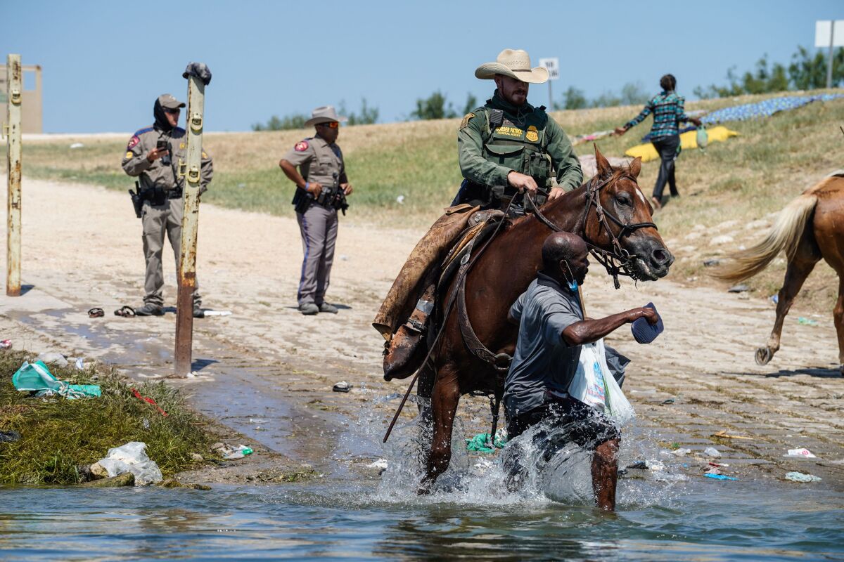 A Border Patrol agent on horseback stops a Haitian migrant.