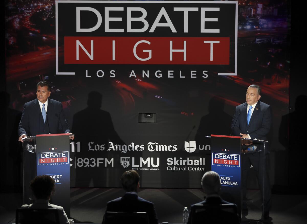 Retired Long Beach Police Chief Robert Luna, left, and Los Angeles County Sheriff Alex Villanueva, right, debate onstage.