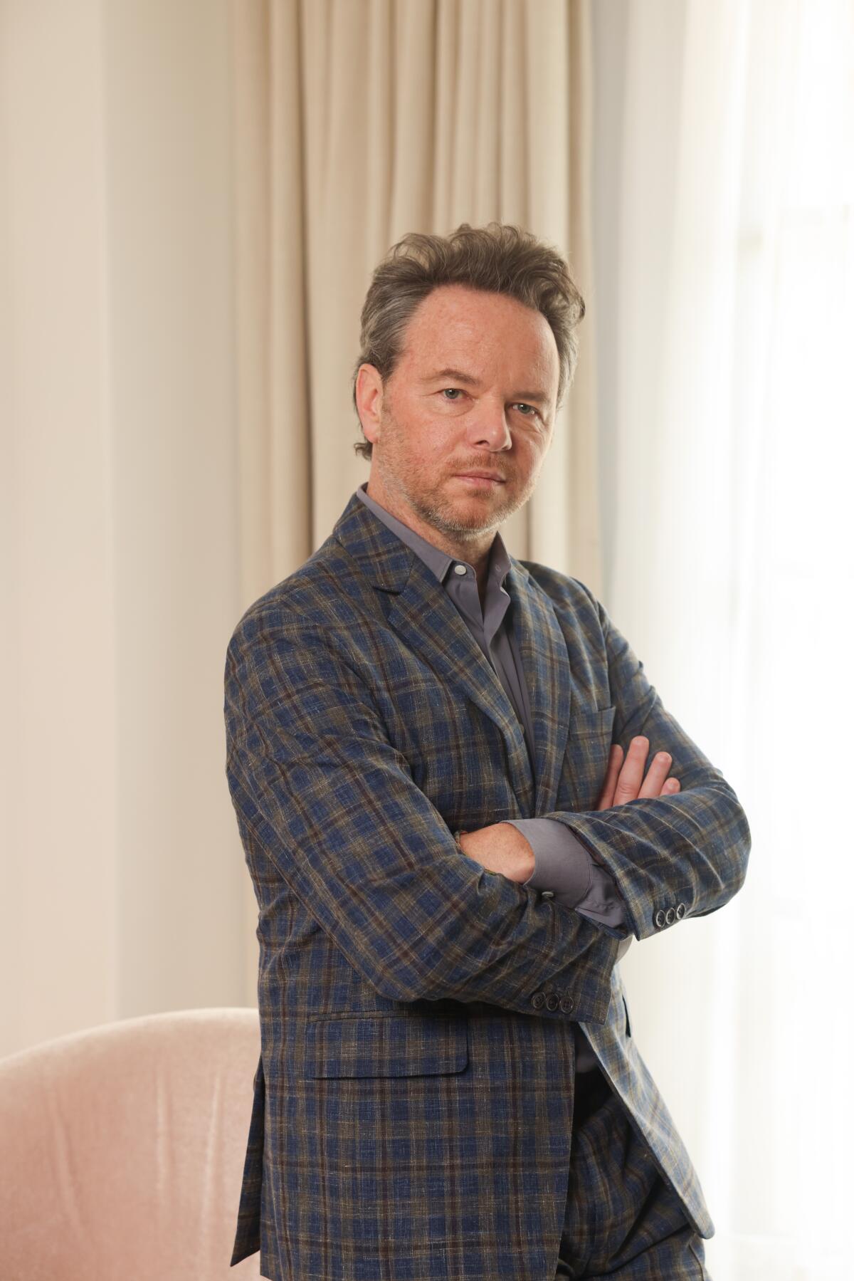 "Fargo" creator and showrunner Noah Hawley stands next to a draped window, arms crossed.