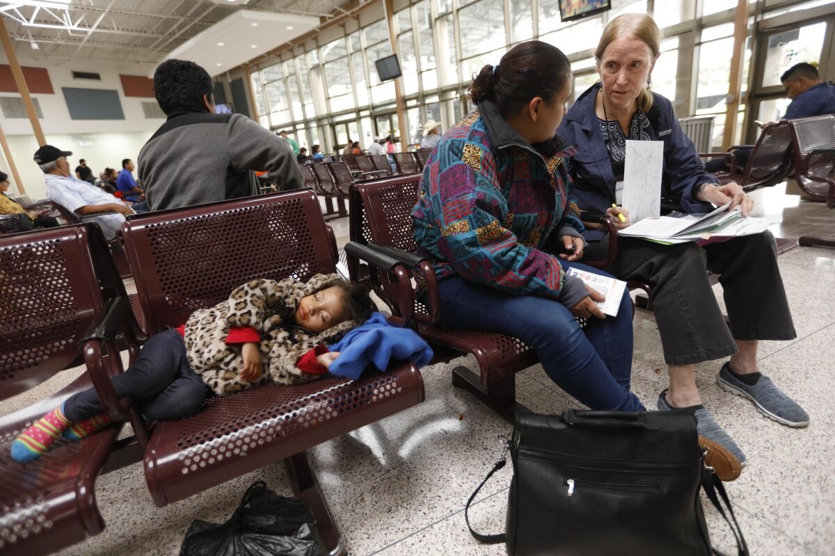 Susan Law, right, a volunteer with Angry Tias and Abuelas, advises Honduran asylum seeker Olga Lara, 29, at the McAllen, Texas, bus station on Thursday. With Lara is her 3-year-old daughter, Alva.