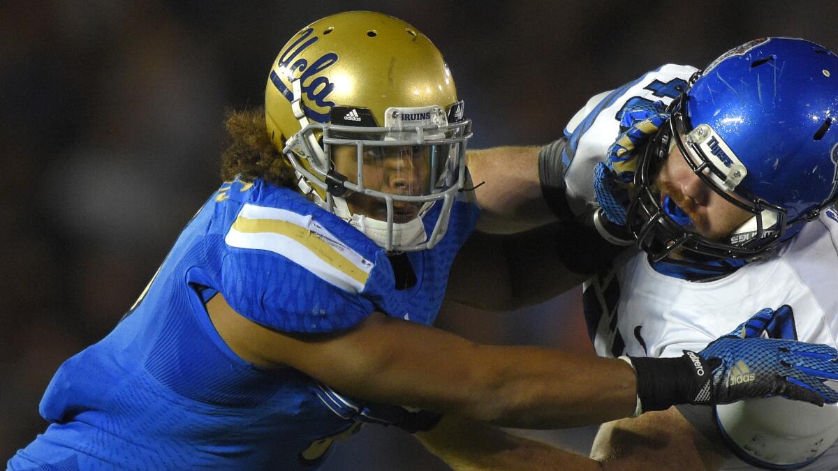 UCLA linebacker Eric Kendricks, left, battles with Memphis tight end Alan Cross during the second half of the Bruins' 42-35 win in September.