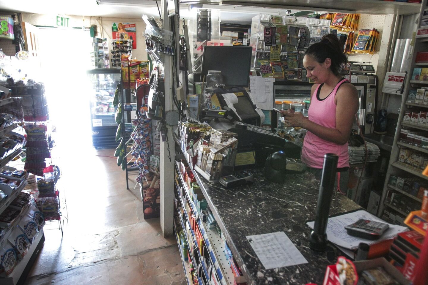 Store employee Sandra Gallegos stands at the cash register while she works in the Petrero Genral Store, which doesn't have any power due to the wildfire there, in Potrero on Monday.