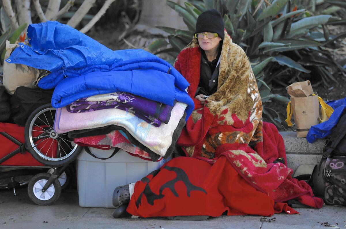 Homeless for the past eight years, Melissa Barrett uses extra blankets to guard against the cold weather while her friend Theresa Sedillo sleeps at her feet at the Santa Ana Civic Center.