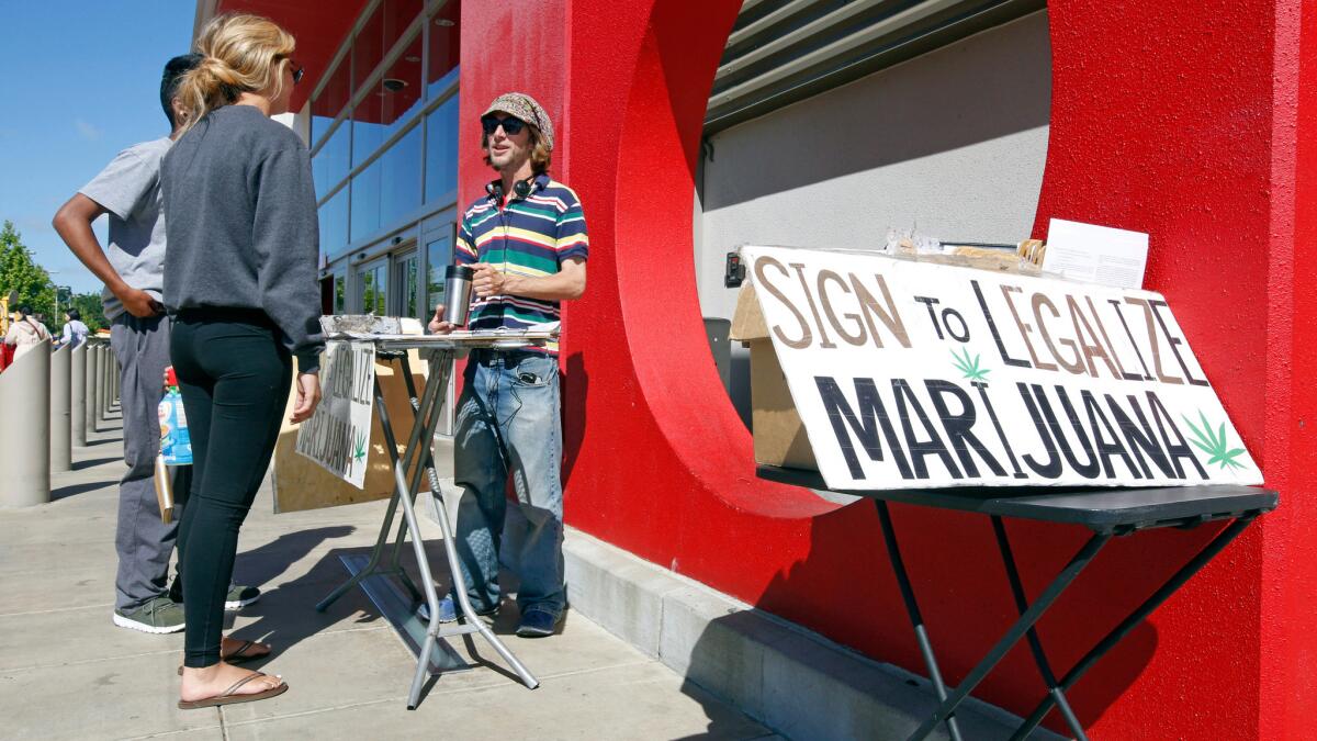 A signature gatherer discusses a petition to legalize marijuana with passersby in Sacramento on April 23.