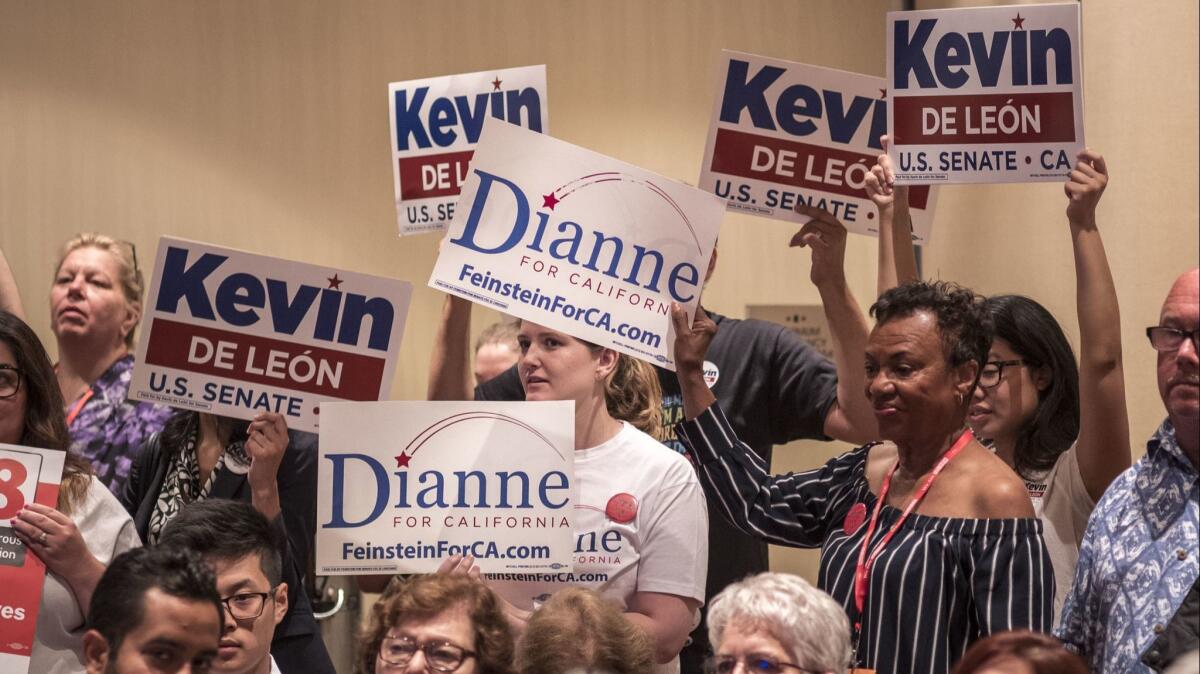 Supporters of Kevin de León and Dianne Feinstein hold signs during a meeting of the state Democratic Party's executive board in Oakland on July 14.