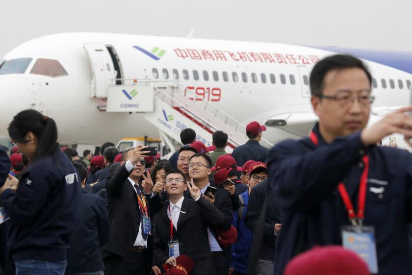 Attendees take photos in front of a Chinese C919 passenger jet after its first flight at Pudong International Airport in Shanghai, Friday, May 5, 2017. The first large Chinese-made passenger jetliner C919 took off Friday on its maiden flight, a symbolic milestone in China's long-term goal to break into the Western-dominated aircraft market. (AP Photo/Andy Wong, Pool)