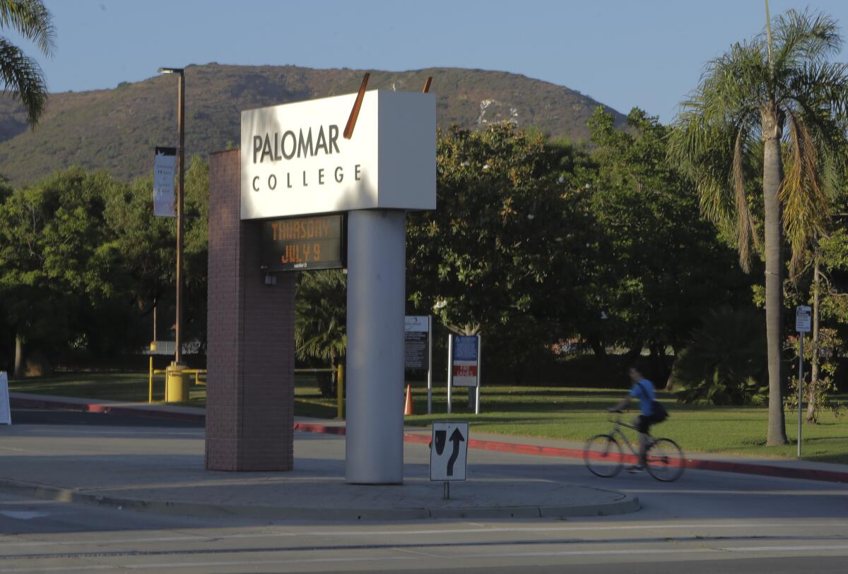 A bicyclist rides past a Palomar College sign