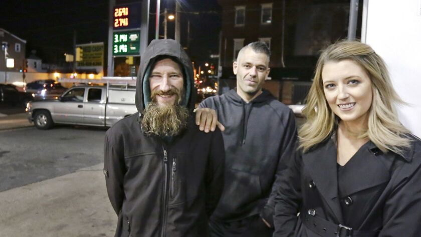In this Nov. 17, 2017 photo, Johnny Bobbitt Jr., left, Kate McClure, right, and McClure's boyfriend Mark D'Amico pose at a Citgo station in Philadelphia.