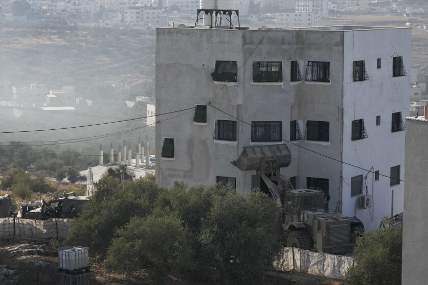 Israeli soldiers surround a Palestinian house during a raid in the village of Deir al-Hatab, near the West Bank city of Nablus, Wednesday, Oct. 5, 2022. The Palestinian Health Ministry says a Palestinian man has been killed by Israeli army fire as troops raided the village in the occupied West Bank. (AP Photo/Majdi Mohammed)