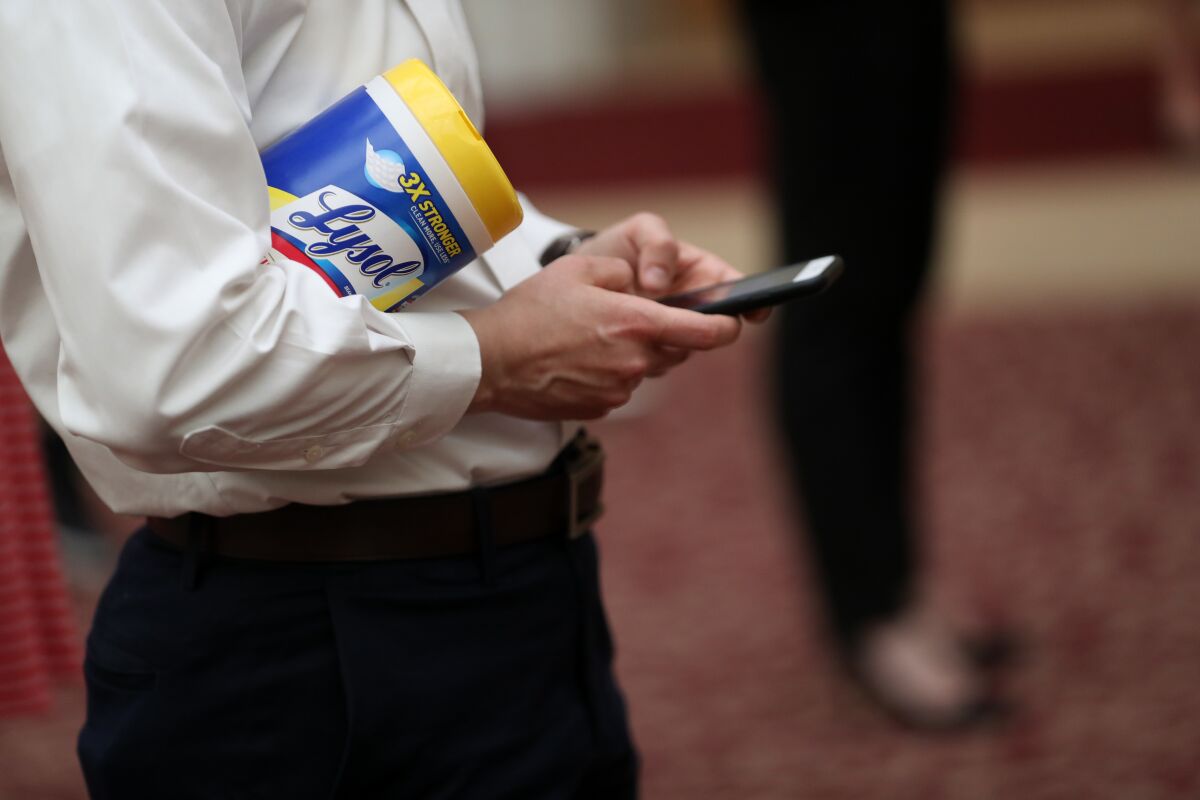 An attendee holds a container of Lysol disinfecting wipes as San Francisco Mayor London Breed (R) speaks during a press conference at San Francisco City Hall on March 16, 2020 in San Francisco, California.