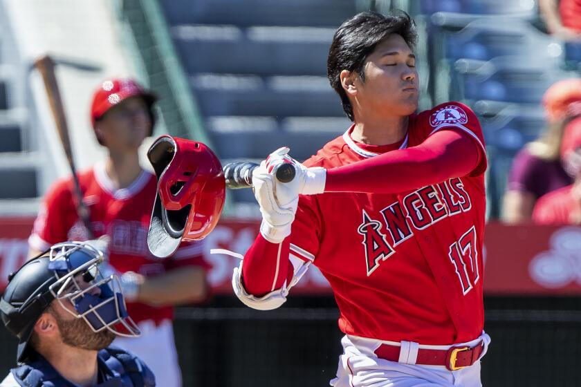 Los Angeles Angels designated hitter Shohei Ohtani, right, knocks off his helmet while fouling off a pitch.