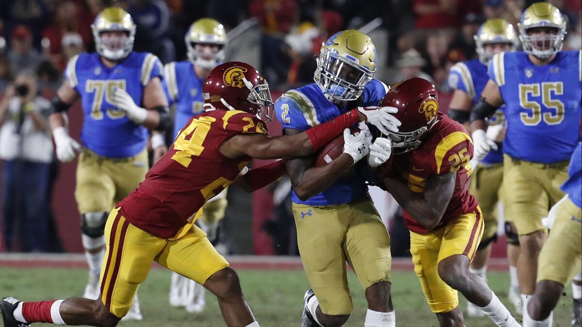 UCLA receiver Jordan Lasley is brought down by USC defenders Isaiah Langley, left, and Jack Jones after making a catch in the second quarter.