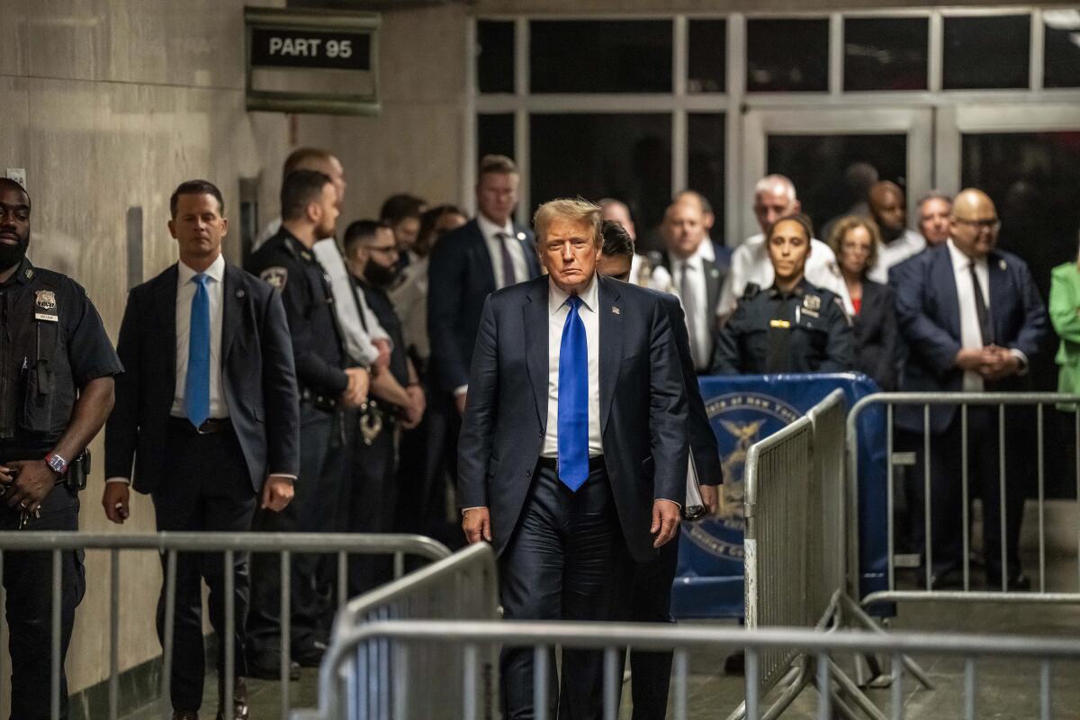Former President Trump walks behind a metal barricade.