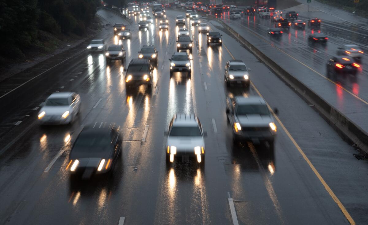 Cars drive in the rain on a freeway.