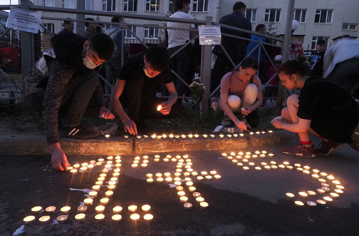 People place lit candles on the ground to form the number 175 after a shooting at school No.175 in Kazan, Russia, Tuesday, May 11, 2021. Russian officials say a gunman attacked a school in the city of Kazan and Russian officials say several people have been killed. Officials said the dead in Tuesday's shooting include students, a teacher and a school worker. Authorities also say over 20 others have been hospitalized with wounds. (AP Photo/Dmitri Lovetsky)
