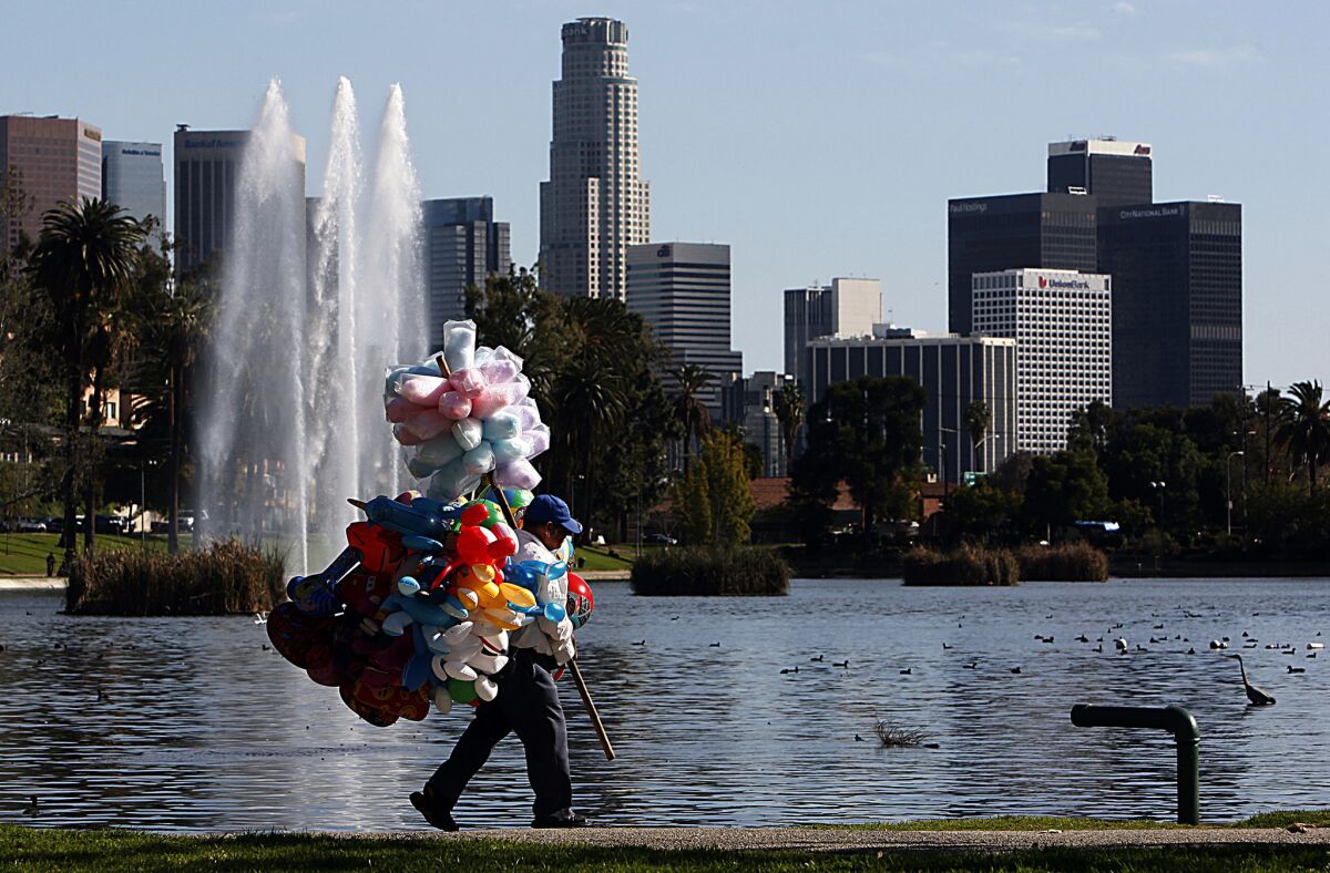 A toy and candy vendor walks on the shore of Echo Park Lake.