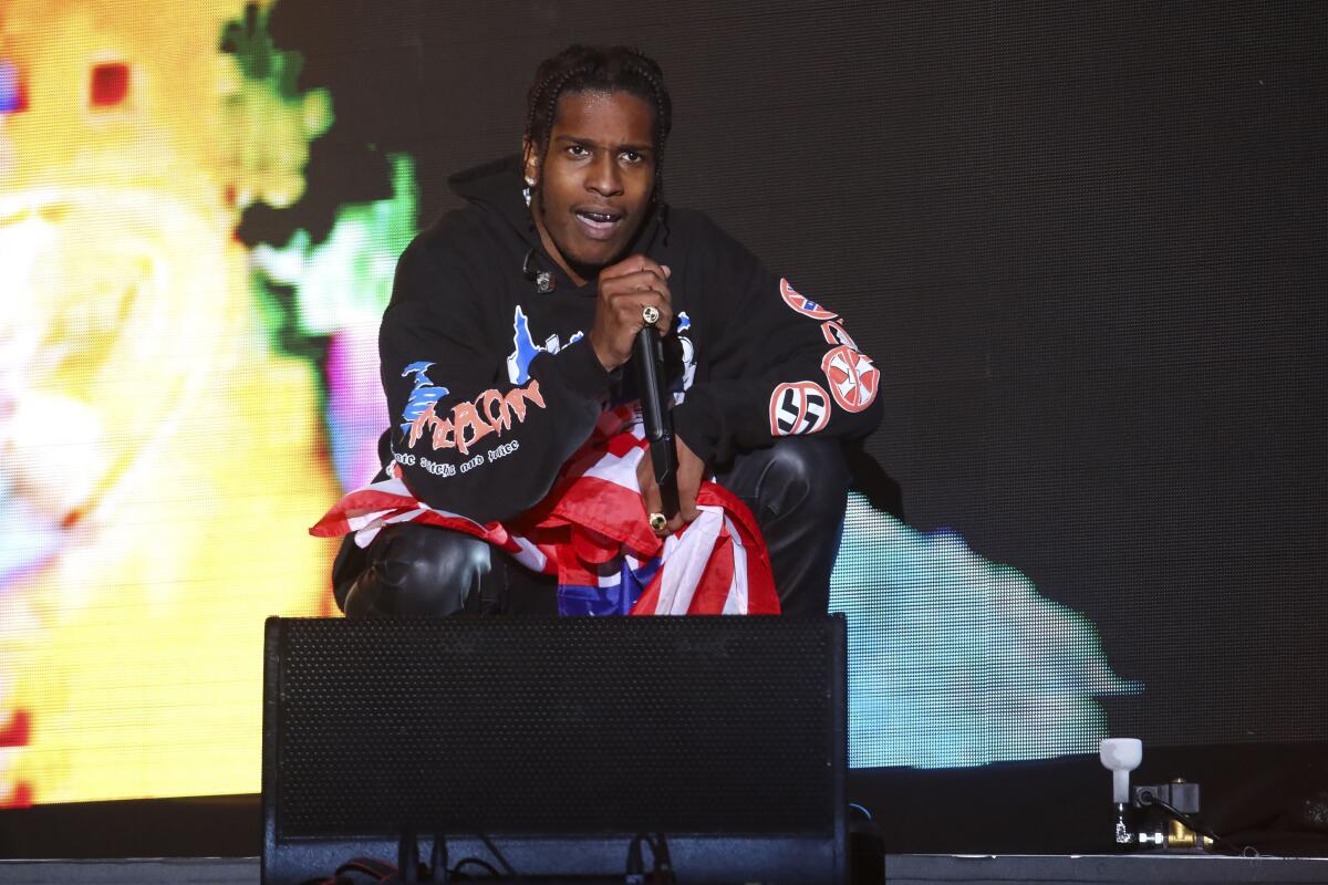ASAP Rocky crouches onstage while holding a microphone.