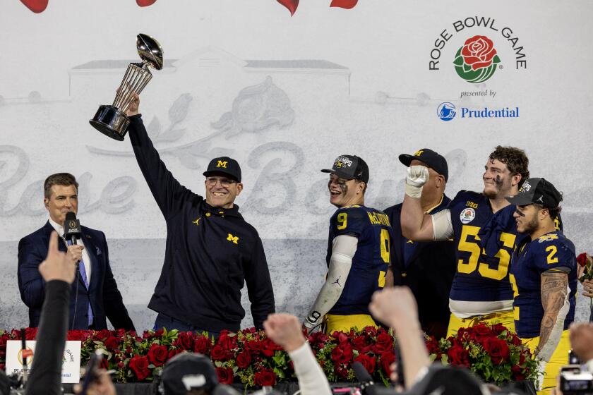 Michigan coach Jim Harbaugh holds the Rose Bowl trophy after the Wolverines' win over Alabama.